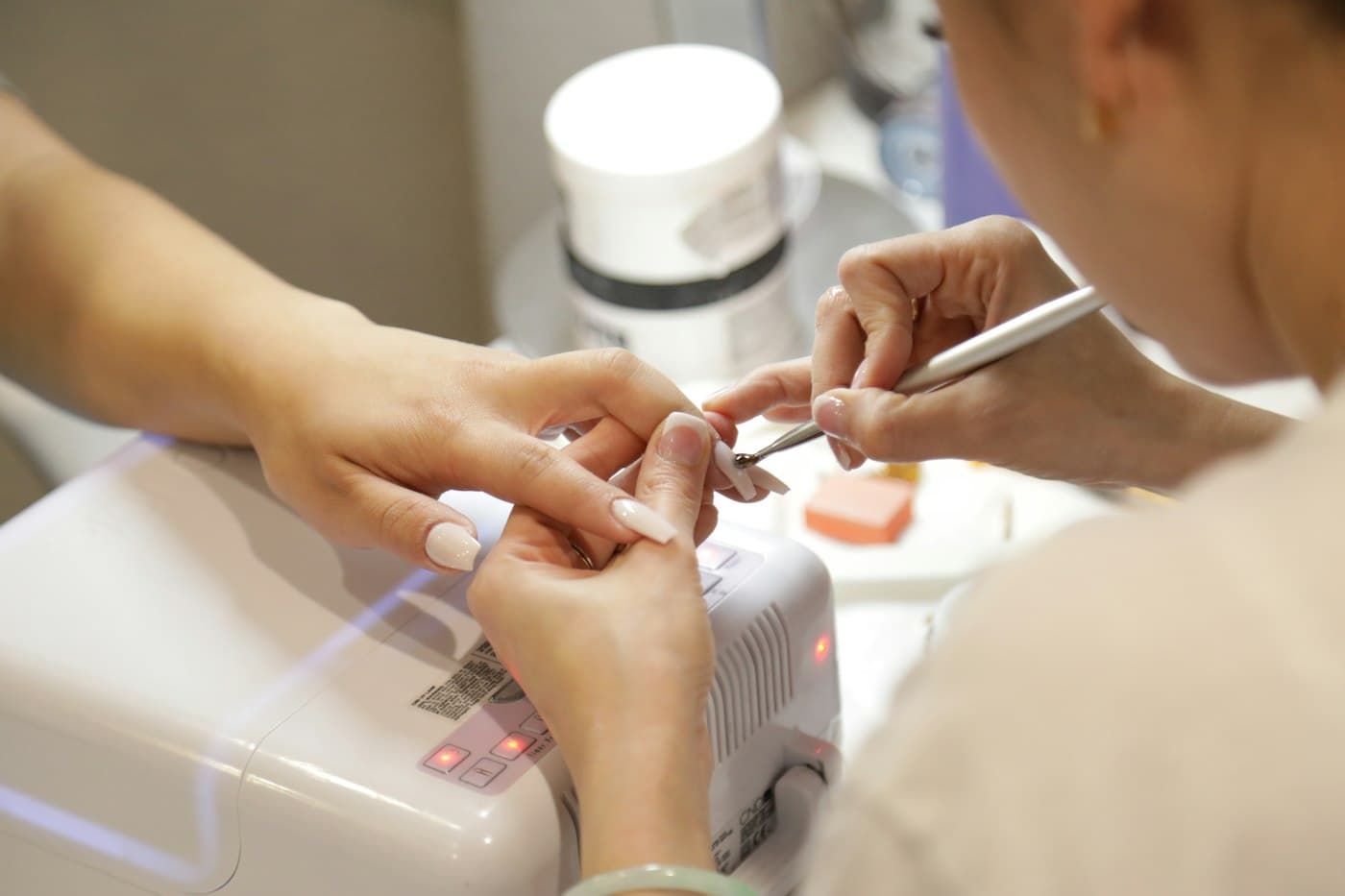 Manicura trabajando sobre las uñas de una clienta en un salón